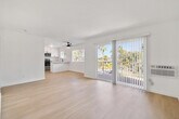 Located at 900 Phillips Street in Vista, CA, this single-story 2-bedroom, 1-bathroom residence offers a clean, modern aesthetic throughout. Light wood-tone flooring runs continuously across all rooms, creating a cohesive and bright interior. The layout includes a dedicated entrance, hallway, and a combined kitchen and living area that serves as the heart of the home.

The kitchen is a standout feature, showcasing white shaker cabinetry with matte black hardware, marble-look quartz countertops, a peninsula for additional prep and dining space, stainless steel appliances, and a window above the sink that draws in natural light. The adjacent living area is open and airy, with a wall-mounted AC unit providing climate control.

Both bedrooms are well-proportioned and bright. The primary bedroom includes a ceiling fan, mirrored sliding closet doors, and an abundance of natural light. The second bedroom also features a ceiling fan and large windows with views of surrounding greenery.

The bathroom is tastefully updated with white shaker vanity cabinetry, quartz countertops, matte black fixtures, a framed mirror, and a tub-shower combination. The overall design palette of crisp white walls, warm flooring, and black accents gives the space a contemporary and inviting character.