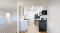 Located at 730 West Algonquin Road in Des Plaines, IL, this 2-bedroom, 1-bathroom unit offers a thoughtfully organized single-floor layout. The galley-style kitchen is a standout feature, showcasing white shaker cabinetry with black hardware, light quartz countertops, a stainless steel sink with a matte black faucet, and a full suite of appliances including a gas range, built-in microwave, dishwasher, and refrigerator. Light wood-look flooring runs throughout the kitchen, complemented by overhead flush lighting and a ceiling fan. The spacious primary bedroom offers generous proportions, natural light from large windows, and soft carpeting underfoot. The second bedroom also features carpet and a door with exterior-facing windows, making it bright and versatile. Both bedrooms include closet space, with the primary featuring a full reach-in closet. The bathroom is clean and modern, with a tub-shower combination, white tile surround, a vanity with a mirrored medicine cabinet, matte black fixtures, and wood-look flooring. A connecting hallway links all rooms efficiently. The overall aesthetic is bright, clean, and move-in ready.