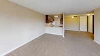 This single-story unit features a well-organized layout across two bedrooms and one bathroom, providing a comfortable and functional living environment. The open living and dining area is carpeted in neutral tones and receives generous natural light through large sliding glass doors fitted with vertical blinds, which open to a private balcony with outdoor views. A ceiling fan overhead adds to the comfort of the space.

The kitchen is positioned adjacent to the living area and accessible via a pass-through counter with light-toned laminate surfaces. Dark walnut-finish cabinetry lines both the upper and lower sections, complemented by a stainless steel sink, a dishwasher, and a range. Tile flooring runs throughout the kitchen.

Both bedrooms are carpeted and feature textured ceilings, neutral wall tones, and closets with built-in shelving and hanging rods. The primary bedroom includes a sliding glass door leading to a private outdoor area with exterior views.

The bathroom is finished with tile flooring, an extended vanity with under-sink storage, and a full tub-and-shower combination enclosed by sliding glass doors. The overall design is clean and straightforward, prioritizing functionality throughout.