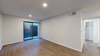 Located at 951 S Oxford Ave in Los Angeles, CA, this well-appointed one-bedroom, one-bathroom unit offers an efficient and functional single-floor layout. Throughout the space, warm wood-look luxury vinyl flooring provides a cohesive aesthetic, complemented by neutral gray walls, white baseboards, and recessed lighting.

The living room is the largest area of the unit, featuring a textured ceiling, recessed lighting, and a sliding glass door that opens to an outdoor area, allowing natural light to fill the room. The open sightlines contribute to a comfortable, airy feel.

The kitchen is designed for practicality, with white cabinetry extending to the ceiling for ample storage, a built-in over-the-range microwave, an electric coil range, and a full-size refrigerator. A dark countertop adds contrast to the clean white surfaces.

The bedroom is a comfortable, private retreat with a window overlooking the exterior, a ceiling fan, a mirrored closet with built-in shelving, and continued wood-look flooring. A dedicated door provides privacy from the rest of the unit.

The bathroom is clean and functional, featuring a combined tub and shower, a white toilet, a vanity with a granite-style countertop, and brushed nickel fixtures and accessories throughout.