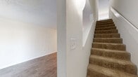 Located at 260 Pelham Rd in Greenville, SC, this two-story residence offers a practical and well-organized layout across two floors. The main level contains the majority of the living space, including a bright living room with wood-look laminate flooring, clean white walls, and a sliding glass door fitted with vertical blinds that invites natural light and provides outdoor access. The galley-style kitchen is efficiently designed with gray shaker cabinets, white countertops, and stainless steel appliances including an electric range, refrigerator, and dishwasher. A full bathroom on the main level features a tub-shower combo with tile surround. Carpeted stairs with textured white walls lead to the upper level, where both bedrooms are situated. The spacious primary bedroom includes a walk-in closet with built-in shelving and ample natural light from a large window with outdoor greenery views. The second bedroom is similarly carpeted with a bright window overlooking the surroundings. A second full bathroom upstairs mirrors the clean, functional design of the first. Throughout the home, neutral tones, white trim, and consistent finishes create a cohesive and move-in ready atmosphere.