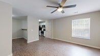 This single-floor residence offers a clean, modern layout designed for comfortable everyday living. The open-concept kitchen and living area form the heart of the home, seamlessly connected by a breakfast bar peninsula with a dark countertop that provides both prep space and casual seating. The kitchen is well-equipped with white shaker-style cabinetry, light countertops, stainless steel appliances including a range, over-the-range microwave, refrigerator, and dishwasher, all set against wood-look luxury vinyl flooring that extends throughout the main living areas.

The spacious living room benefits from natural light through a window with blinds and is fitted with a ceiling fan, creating a bright and airy atmosphere. A dedicated laundry area is conveniently accessible from within the unit.

The bedrooms are finished with soft wall-to-wall carpeting and ceiling fans, offering a comfortable retreat. Each bedroom includes closet space, with at least one featuring a built-in shelving system for added organization. The neutral, light gray wall tones throughout the residence create a cohesive and versatile backdrop. The textured ceilings and clean white trim complete the tidy, move-in-ready aesthetic of this thoughtfully designed single-level home.