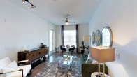 This model unit at 5080 Camino Del Arroyo in San Diego showcases a thoughtfully designed single-floor layout with contemporary finishes throughout. The open-concept living and dining area is anchored by rich hardwood-style flooring, a ceiling fan, and large windows dressed with elegant draping curtains that flood the space with natural light. The living area offers a welcoming ambiance, while the adjacent dining space benefits from expansive views of the surrounding neighborhood.

The kitchen is a standout feature, boasting dark espresso cabinetry that extends to the ceiling for ample storage, stainless steel appliances including a French-door refrigerator and gas range, a classic subway tile backsplash, and a bright white countertop with a peninsula-style island for casual dining or food preparation.

The unit includes multiple well-proportioned bedrooms, each carpeted for comfort and fitted with ceiling fans and generous windows. The primary bedroom includes a spacious walk-in closet, providing extensive storage. Additional bedrooms are equally bright and versatile.

The bathrooms are finished with neutral tile, dark vanity cabinetry, white countertops, and a combination tub and shower with a curved curtain rod. Open shelving adds additional storage and a clean, organized aesthetic throughout. The overall design balances modern style with functional living.