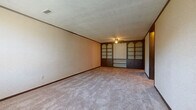 Located at 32 Cedargate Ct in Galion, Ohio, this single-floor, two-bedroom, one-bathroom home offers a straightforward and functional layout. Throughout the space, textured ceilings and dark wood baseboards provide consistent detailing, while neutral wall tones create a clean, understated backdrop.

The generously sized primary bedroom is a standout feature, boasting an expansive built-in wall unit with arched display shelving and cabinetry finished in dark wood — an eye-catching focal point that adds both character and practical storage. A ceiling fan with a light fixture keeps the room comfortable, and plush carpeting runs throughout. The second bedroom is comparably appointed with carpet flooring, a ceiling fan, and a window that brings in natural light, giving the room an open and airy feel.

The kitchen is compact and efficient, featuring wood-fronted cabinetry, light countertops, tile flooring, and a full-size refrigerator, providing all the essentials in a well-organized space. A connecting hallway links the rooms cohesively.

The full bathroom includes a wood-vanity with a light countertop, a tub/shower combination with a white surround, a toilet, and tile flooring — offering a clean and complete set of amenities. Overall, this home presents a practical and comfortable living space suited for easy, everyday living.