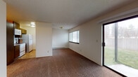 Located at 515 South Farr Road in Spokane, Washington, this single-floor unit offers a practical and well-organized layout suited for comfortable everyday living. The open living and dining area is generously sized, finished with warm brown carpeting and served by baseboard heating. A large sliding glass door fills the space with natural light and provides direct access to the outdoors, while a window with blinds adds additional brightness. The kitchen is positioned adjacent to the living area and features a pass-through counter with a stainless steel sink, dark wood cabinetry, a white range, microwave, and refrigerator — offering both functionality and a defined workspace. A central hallway connects the private areas of the unit, lined with dark-framed doors leading to multiple carpeted bedrooms. Each bedroom includes a window with blinds and baseboard heating, providing a comfortable and well-lit environment. The bathroom is finished with tile flooring and includes a full tub/shower combination, toilet, and a vanity with countertop storage. Textured ceilings are consistent throughout the unit, contributing to a cohesive interior aesthetic. This unit presents a clean, straightforward floor plan with convenient access to both indoor and outdoor living.