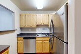 Located at 601 Four Mile Rd in Alexandria, Virginia, this one-bedroom, two-bathroom residence offers a well-organized, single-floor layout designed for efficient and comfortable living. The open living room is a welcoming centerpiece, showcasing warm parquet hardwood flooring that extends throughout the unit, complemented by bright white walls and a ceiling fan with light fixture. A large window frames views of lush greenery, filling the space with natural light and a connection to the outdoors. A convenient pass-through window connects the living area to the kitchen, which features light wood cabinetry, dark granite-style countertops, stainless steel appliances including a dishwasher and refrigerator, and clean tile flooring. The bedroom offers a cozy retreat with its own window overlooking the greenery, a ceiling fan, and the same rich parquet flooring found throughout. A dedicated closet with louvered doors provides ample storage. The two bathrooms include a full bath with a wood-toned vanity, a large mirror with vanity lighting, and warm tile floors, as well as a secondary bathroom with classic mosaic tile flooring and a shower with a curtain enclosure. The overall ambiance is clean, bright, and functional, making this residence a practical and comfortable home in Alexandria.