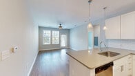 Located at 201 Sawyer Cir in Charleston, SC, this single-story 3-bedroom, 2-bathroom home offers a thoughtfully designed open floor plan with clean, modern finishes throughout. A welcoming hallway leads into the open-concept kitchen and living area, where light wood-style flooring, recessed lighting, and soft neutral walls create a bright, airy atmosphere. The kitchen is well-appointed with white shaker cabinets, a subway tile backsplash, gray countertops, a kitchen island with pendant lighting, and a full suite of stainless steel appliances. The adjacent living room is spacious and filled with natural light from large windows and a glass door that opens to a private balcony, complemented by a ceiling fan overhead. The generously sized primary bedroom features its own outdoor access, hardwood-style flooring, a ceiling fan, and a dedicated closet with built-in wire shelving. Two additional bedrooms offer plush carpet, ceiling fans, and ample natural light through slatted blinds. Both bathrooms are finished with white cabinetry, stone-tone countertops, and wood-style flooring; the primary bath includes a walk-in glass-door shower. Two closets provide practical storage throughout the home, rounding out this well-appointed Charleston residence.