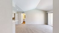 Located at 2301 NW 122nd St in Oklahoma City, OK, this one-bedroom, two-bathroom residence offers a thoughtfully designed layout across a single floor. The living room serves as the heart of the space, featuring vaulted ceilings that lend an open, airy feel, a tile-surround fireplace, soft carpeting, and a sliding glass door that opens to a balcony with community views. The kitchen is efficiently laid out with white shaker-style cabinetry, a stainless steel refrigerator, a gas range, and a peninsula with a sink that provides both additional prep space and a natural transition into the living area. Wood-look flooring runs through the kitchen, adding warmth and durability. The bedroom is a comfortable retreat with plush carpeting, a ceiling fan, and a window that brings in natural light with views of the surrounding community. It is complemented by a generously sized walk-in closet outfitted with wrap-around shelving and hanging rods for ample storage. The two bathrooms include a well-appointed vanity with white cabinetry, brushed nickel hardware, and a lighted mirror, alongside a full tub-and-shower bathroom with wood-look tile flooring. The overall aesthetic is clean and neutral, creating a bright and welcoming atmosphere throughout.