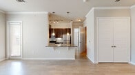 Located at 26493 E University Dr in Little Elm, TX, this well-appointed one-bedroom, one-bathroom residence offers a thoughtfully designed single-floor layout. Light wood-style flooring and crown molding run throughout, lending a clean, cohesive aesthetic to the entire space. The open-concept living, dining, and kitchen area serves as the heart of the home, where natural light pours in through multiple windows. The kitchen features rich dark-wood cabinetry, granite countertops, a tile backsplash, and a full suite of stainless steel appliances, including a refrigerator, range, and microwave. A peninsula with a granite overhang provides casual seating and separates the kitchen from the living and dining areas, while pendant lighting adds a refined touch overhead. The spacious bedroom offers a comfortable retreat with its own closet and easy access to the full bathroom. The bathroom is appointed with a granite-topped dark-wood vanity and a soaking tub and shower combination surrounded by large-format gray tile. Additional highlights include a dedicated pantry, in-unit laundry, and track lighting in select areas, completing this functional and attractive residence.