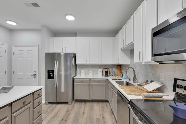 Elegant modern kitchen showcasing sleek stainless steel appliances, pristine white cabinetry, and stylish wood flooring, perfect for culinary creativity. - Avia Lowry