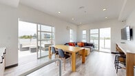 This 350 square foot amenity space, located on the 6th floor of a building in Saanich, BC, offers a modern and multifunctional environment. The open-concept layout maximizes the use of space, seamlessly blending indoor and outdoor areas. The interior features a well-appointed kitchenette with sleek cabinetry and appliances, perfect for preparing snacks or beverages. The lounge area is furnished with comfortable seating, including a plush sofa adorned with vibrant orange accent pillows, creating a welcoming atmosphere. Large windows flood the space with natural light and provide expansive views of the surrounding area. A standout feature is the spacious outdoor terrace, equipped with contemporary patio furniture and a built-in barbecue, ideal for al fresco dining or relaxation. The light wood flooring, neutral color palette, and thoughtful lighting create a bright and airy ambiance throughout. This versatile amenity space is designed to cater to various activities, from casual gatherings to quiet relaxation, offering residents a stylish and functional extension of their living space.