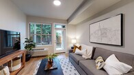 Located at 13470 SE 162nd Ave in Happy Valley, Oregon, this single-story unit offers a thoughtfully designed layout that balances modern finishes with functional living spaces. Light wood-tone flooring flows throughout the main areas, creating a warm and cohesive aesthetic.

The living room is a bright, inviting space anchored by large windows and a glass-panel door that opens directly to a private outdoor area, allowing natural light and views of lush greenery to fill the room. A wall-mounted HVAC unit provides convenient climate control.

The kitchen is well-appointed with dark espresso cabinetry, granite countertops, white subway tile backsplash, and a full suite of stainless steel appliances, including a refrigerator, electric range, microwave, and dishwasher. A peninsula with seating for two pendant lights overhead serves as both a functional workspace and casual dining area, opening seamlessly into the living space.

The bedroom features plush carpeting and neutral tones, offering a quiet retreat. The bathroom includes wood-look flooring, granite-topped vanity cabinetry, and a full soaking tub with shower. The overall ambiance is clean, contemporary, and well-suited for comfortable everyday living.