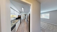 Located at 311 S Lasalle St in Durham, NC, this single-floor, two-bedroom, one-bathroom residence offers a functional and straightforward layout. The combined kitchen and living area forms the heart of the home, with the galley-style kitchen featuring white cabinetry, dark countertops, a stainless steel refrigerator, electric range, and a double sink — all set atop warm hardwood-style flooring. A pass-through window connects the kitchen to the living area, which is finished with neutral carpet and a ceiling fan, creating a comfortable, open feel. Both bedrooms are carpeted and finished in soft grey tones, each benefiting from windows that bring in natural light and views of surrounding greenery. The primary bedroom is generously sized and includes two closets, offering ample storage. The second bedroom also features a window with outdoor views, maintaining the light and airy feel consistent throughout the unit. The full bathroom is equipped with a single-sink vanity, toilet, and a tub-shower combination, finished with hardwood-style flooring. Clean grey walls, white trim, and consistent neutral tones throughout the unit create a cohesive, move-in-ready atmosphere well-suited for comfortable everyday living.