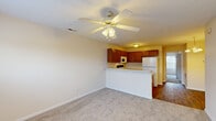 Located at 2580 Cumberland Creek Dr in Fayetteville, NC, this two-bedroom, one-bathroom unit offers a practical and well-organized single-floor layout. The open living and dining area is finished with plush carpeting and features a ceiling fan with integrated lighting, creating a comfortable, airy atmosphere. A peninsula counter connects the living space to the kitchen, which is equipped with warm wood-toned cabinetry, light countertops, a double-basin sink, an electric range, built-in microwave, and a full-size refrigerator. Durable wood-style flooring runs throughout the kitchen, adding a clean contrast to the carpeted areas. The primary bedroom is a generously sized retreat with carpet flooring, a ceiling fan, and a window that brings in natural light. The second bedroom also features wood-style flooring and neutral walls, offering flexibility as a guest room or home office. The full bathroom includes a tub and shower combination with clean white surround. A dedicated closet provides washer and dryer hookups along with a wire shelving system, adding practical utility to the space. Clean neutral tones throughout give the unit a bright and move-in-ready feel.