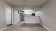 This single-floor unit offers a clean, modern aesthetic with consistent wood-style luxury vinyl flooring flowing throughout every room. The open-concept kitchen is a standout feature, equipped with white shaker cabinetry, dark countertops, a classic subway tile backsplash, and a full suite of stainless steel appliances including a refrigerator, electric range, over-the-range microwave, and dishwasher. A raised tray ceiling with recessed lighting adds architectural depth to the kitchen area, while a peninsula with a breakfast bar separates it from the living space, creating a functional and social layout. The living and dining areas are bright and open, benefiting from natural light through windows fitted with blinds. Ceiling fans are installed in the main living area and bedrooms, providing both comfort and ambient lighting. The bedrooms offer a comfortable, neutral palette with textured ceilings and windows that invite natural light. The bathroom is well-finished, featuring large-format, wood-grain ceramic tile surrounding a full soaking tub and shower combination, paired with brushed nickel fixtures and matching wood-style flooring. Neutral wall tones, clean white trim, and consistent finishes throughout give the entire space a cohesive and updated feel.