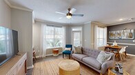 Located at 80 Oak Ave in Mount Pleasant, South Carolina, this well-appointed one-bedroom, one-bathroom residence offers a thoughtfully designed single-level floor plan. The combined living and dining area serves as the heart of the home, bathed in natural light from multiple large windows with views of lush greenery. The living room features wood-look flooring, crown molding, a ceiling fan, and a textured ceiling, creating a warm and inviting atmosphere. A dedicated dining nook with a large window and chair rail detailing provides an ideal space for meals. The kitchen is outfitted with crisp white cabinetry, a clean white countertop peninsula, stainless steel appliances including a range, microwave, and refrigerator, and light hardwood-style flooring. The spacious primary bedroom is carpeted for comfort, featuring dual windows, a ceiling fan, and ample natural light. A walk-in closet with wire shelving offers generous storage. The bathroom includes a full tub and shower combination with white tile surround. A hallway connects all areas efficiently, completing this functional and stylish layout ideally situated in the heart of Mount Pleasant.