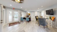 This 1000 square foot space in Raleigh, NC, comprises a well-equipped fitness center and an inviting lounge area. The fitness center boasts vibrant teal walls, creating an energizing atmosphere. It's outfitted with a comprehensive range of modern exercise equipment, including treadmills, ellipticals, stationary bikes, and weight training machines. The room features recessed lighting, ceiling fans for comfort, and large mirrors to assist with proper form during workouts.

Adjacent to the gym is a stylishly appointed lounge area. This space serves as a reception and relaxation zone, with light-colored walls and ample natural light from large windows. The decor includes comfortable seating, a unique sunburst ceiling fixture, and tasteful artwork. A small desk area suggests this may double as a check-in point for the fitness center.

The entire space is unified by light wood-look flooring, creating a cohesive and contemporary feel. The layout appears thoughtfully designed to maximize functionality while maintaining an open, airy ambiance. This amenity space likely serves as a valuable feature for residents of the apartment complex, offering both fitness opportunities and a social gathering area.
