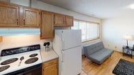 This single-floor residence offers a practical and well-organized layout across multiple rooms, all unified by warm-toned hardwood-style flooring and neutral white walls that create a clean, cohesive aesthetic throughout. Textured ceilings and wood-trimmed windows are consistent design elements found in each room, lending a modest but cohesive character to the space.

The kitchen is equipped with an abundance of oak cabinetry providing generous storage, light-colored countertops, a double-basin stainless steel sink, a dishwasher, and an electric range. A wide window in the adjoining area allows natural light to flow into the space, which opens toward a small living area.

Multiple bedrooms are present, each featuring wood-trimmed windows that overlook the surrounding neighborhood and greenery, flush-mount ceiling light fixtures, and ample floor space suitable for various furniture arrangements. The rooms share a consistent, understated design that prioritizes functionality.

Two full bathrooms serve the unit, each featuring a tub-shower combination with curtain, a vanity with storage, a mirror, and tile flooring. The bathrooms are straightforward in design with clean, white fixtures throughout.

Overall, the space presents a functional and neutral environment well-suited for comfortable everyday living.