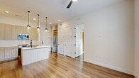 Located at 2825 W 11th St in Houston's desirable Heights neighborhood, this thoughtfully designed 2-bedroom, 2-bathroom residence offers a clean, contemporary aesthetic across a single floor. Warm wood-look flooring flows throughout, complementing the bright, neutral palette that defines every room.

The open-concept kitchen, dining, and living area serves as the heart of the home. The kitchen features a large center island with a white quartz countertop and an integrated sink, light wood cabinetry, stainless steel appliances, and striking pendant lights with glass globe shades. A ceiling fan overhead and French doors with transom windows at the far end of the living area invite natural light and offer outdoor views.

Both bedrooms are generously proportioned with hardwood-style flooring, ceiling fans, and ample natural light from large windows. The primary bedroom includes a spacious walk-in closet outfitted with built-in shelving, hanging rods, and wood accents for well-organized storage. Three closets total provide excellent storage throughout the unit.

The bathrooms feature elegant marble-look tile on both floors and walls, with a soaking tub and shower combo accented by sleek matte black fixtures. A dedicated laundry area and multiple hallways add practical convenience. The overall ambiance is modern, clean, and move-in ready.