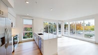 Located at 7007 SW Hampton St in Tigard, Oregon, this single-story home offers four bedrooms and two bathrooms across a well-designed, open floor plan. The combined kitchen and living area serves as the heart of the home, showcasing a sleek, modern aesthetic with white cabinetry, a large center island with quartz countertops, stainless steel appliances, and recessed lighting. Oversized windows and sliding glass doors flood the space with natural light and provide views of the surrounding greenery. Light hardwood flooring runs throughout, lending warmth and continuity to every room. The bedrooms are bright and well-proportioned, each benefiting from large windows that frame outdoor views and allow ample sunlight. The primary bedroom includes a double-door closet, adding practical storage. The bathrooms feature clean, modern finishes, including white cabinetry with built-in shelving and a glass-enclosed walk-in shower. A dedicated laundry room houses a full-size washer and dryer. The hallway connects the rooms efficiently, featuring a sliding barn door accent and black hardware details that complement the home's contemporary style. A wall-mounted mini-split system provides climate control throughout.