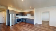 Located at 22199 NE Sandy Blvd in Fairview, Oregon, this well-appointed two-bedroom, two-bathroom residence offers a thoughtfully designed single-floor layout with modern finishes throughout. The open-concept kitchen and living area serves as the heart of the home, showcasing rich wood-tone flooring, recessed lighting, and a clean, contemporary palette. The kitchen is outfitted with sleek charcoal cabinetry, white countertops, a stainless steel refrigerator, range, and microwave, along with a built-in sink — providing both style and functionality. The living area flows naturally from the kitchen, offering generous space filled with natural light. Both bedrooms feature wood-look flooring, crisp white walls, and windows with views of the surrounding greenery and neighborhood. The spacious primary bedroom includes a sliding barn-style door for a modern touch. The bathrooms are finished with matching dark cabinetry, white countertops, and wood-look flooring, maintaining a consistent aesthetic throughout. A private balcony accessible from the living area offers impressive elevated views of the mountains, treetops, and surrounding Fairview community — an ideal spot to enjoy the natural beauty of the Pacific Northwest.
