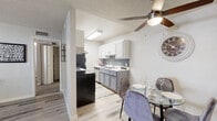 Located at 7700 E Speedway Blvd in Tucson, Arizona, this single-floor residence offers a thoughtfully updated interior with a clean, contemporary aesthetic. Light-toned luxury vinyl plank flooring runs throughout the main living areas, complemented by neutral wall tones and textured ceilings that lend a cohesive feel to the space.

The living room is generously proportioned, featuring a large window that invites natural light and provides a welcoming atmosphere. It flows seamlessly into the dining area, which is highlighted by a ceiling fan with integrated lighting — a practical touch well-suited to the Arizona climate.

The kitchen is efficiently laid out with a galley-style design, showcasing two-tone cabinetry — white upper cabinets paired with gray lower cabinets — set against a classic subway tile backsplash. Light countertops, a stainless steel electric range, and a black refrigerator complete the functional cooking space.

The two bedrooms are carpeted for comfort, each featuring windows with blinds that allow for natural light and privacy. The bathroom continues the updated design language with gray shaker-style cabinetry, a white countertop vanity, a framed mirror, and light wood-look flooring, creating a clean and modern finish throughout.