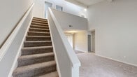 Located at 100 Vanderbilt Ln in Spartanburg, SC, this two-story home offers 3 bedrooms, 3 bathrooms, and a well-organized layout across two floors. The main level commands attention with its dramatic two-story ceiling height, visible from the open living area and staircase. Plush carpeting flows through the living spaces, while wood-look flooring accents transitional areas. A standout fireplace with a sleek black surround serves as a focal point in the main living area, which is bathed in natural light from well-placed windows. The kitchen is equipped with dark cabinetry, white countertops, black appliances, and a classic white subway tile backsplash. Each of the three bedrooms offers carpeted floors and dedicated closet space, including walk-in and sliding-door closets. The primary bedroom features vaulted ceilings, enhancing its sense of openness. The three bathrooms are finished with white vanities, modern brushed nickel fixtures, and framed mirrors. One bathroom includes a full tiled tub-shower combination. A dedicated laundry room and six closets throughout provide ample storage. The upper floor, accessible via a carpeted staircase with white railings, adds additional bedroom and bathroom accommodations.