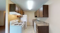 Located at 10015 N Colfax Rd in Spokane, Washington, Unit 44 is a single-floor residence thoughtfully designed for comfortable everyday living. The layout flows efficiently through well-defined spaces, each finished with practical materials and neutral tones throughout.

The galley-style kitchen is equipped with dark wood cabinetry offering generous upper and lower storage, granite-patterned countertops, a stainless steel sink, and white appliances including an electric range, refrigerator, and dishwasher. Light tile flooring completes the clean, functional aesthetic.

The living area is carpeted and bathed in natural light, featuring a sliding glass door that opens to a private balcony with outdoor views — an inviting extension of the living space. A baseboard heating system runs along the walls, providing consistent warmth throughout the unit.

The bedroom is a comfortable, carpeted retreat with a window allowing natural light, a baseboard heater, and direct access to a spacious walk-in closet. The adjoining bathroom features a wide vanity with dark wood cabinetry, a large mirror, tile flooring, and a full soaking tub with a tiled shower surround.

Textured ceilings are present throughout, and the entryway provides a welcoming transition into the main living space.