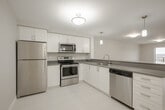 Located at 996 Paisley Rd, Suite 511 in Guelph, Ontario, this well-appointed one-bedroom, one-bathroom unit offers a thoughtfully designed open-concept layout across a single floor. The kitchen is a functional highlight, featuring white shaker-style cabinetry, grey composite countertops, stainless steel appliances including a refrigerator, stove, built-in microwave, and dishwasher, along with light tile flooring. A peninsula with pendant lighting connects the kitchen to the combined dining and living area, which is finished with warm wood-tone laminate flooring and large sliding glass doors that flood the space with natural light and lead to a private balcony with open outdoor views. The bedroom is a comfortable size, offering mirrored sliding closet doors and the same laminate flooring, with easy access to the main living area. The bathroom includes a full soaker tub with chrome fixtures. A dedicated in-unit laundry area houses a full-sized top-load washer and dryer, adding everyday convenience. Neutral tones and clean finishes throughout create a bright, modern ambiance suited for comfortable living.