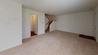 Located at 401 Bedford Ln in New Castle, Delaware, this two-floor home offers a practical and comfortable layout designed for everyday living. The main level features a spacious living area finished with neutral-toned carpet, a ceiling fan, and a sliding glass door with vertical blinds that opens to an outdoor space, allowing natural light to fill the room. Adjacent to the living area, a dedicated entryway provides access to the staircase connecting both floors, with warm hardwood-style flooring guiding the way into the functional areas of the home. The kitchen is well-appointed with rich, dark cabinetry, light granite-style countertops, and black appliances including a range, over-the-range microwave, and refrigerator, all set atop durable hardwood-style flooring. A dedicated laundry room houses a stacked washer and dryer unit, adding everyday convenience. The bathroom features a clean, white tub-shower combination with chrome fixtures. Upstairs, the bedrooms offer comfortable carpeted floors and generous natural light through blinded windows. The primary bedroom stands out with dual closets, providing ample storage. Additional bedrooms are bright and versatile. Throughout the home, a clean, neutral palette creates a move-in-ready atmosphere well-suited for a variety of living arrangements.