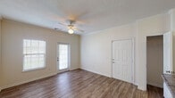 This single-floor unit offers a practical and comfortable layout across one bedroom and one bathroom. The living area features wood-look laminate flooring, neutral-toned walls, and a ceiling fan with a light fixture, creating a bright and airy atmosphere. A glass-paned door provides natural light and outdoor access, while a side window with blinds adds to the room's openness.

The kitchen is well-equipped with warm-toned wooden cabinetry offering generous storage, dark granite-style countertops, and black appliances including a refrigerator, electric range, and dishwasher. A peninsula island provides additional counter space and serves as a functional divide between the kitchen and living area. Wood-look flooring carries through this space seamlessly.

The bedroom is a comfortable retreat featuring plush carpeting, a ceiling fan, and a window with blinds that allows natural light to filter in. The neutral color palette maintains a calm, cohesive feel throughout.

The full bathroom includes a tub-shower combo with white tile surround, a vanity with dark countertop, wood-toned cabinetry beneath, and wood-look flooring. The layout is clean and efficient. Overall, the unit delivers a functional, cohesive design with consistent finishes throughout.
