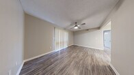 Located in Ridgeland, Mississippi, this well-designed one-bedroom, one-bathroom unit offers a functional and comfortable layout across a single floor. The open living room and kitchen area serves as the heart of the space, featuring durable wood-look flooring, neutral warm-gray walls, and a textured ceiling. A ceiling fan with a built-in light fixture provides both comfort and illumination, while a large sliding glass door dressed with vertical blinds floods the room with natural light. The kitchen is outfitted with rich dark cabinetry, light countertops, a stainless steel sink, dishwasher, and an electric range, providing ample storage and functionality. The spacious bedroom is finished with plush wall-to-wall carpet, a ceiling fan, and a window with blinds that allows for natural light and ventilation. A dedicated closet adds convenient storage. The bathroom features wood-look flooring, dark vanity cabinetry with a white countertop, a large mirror, and a tub-shower combination with white tile surround and brushed nickel fixtures and grab bars. Clean white trim and consistent neutral tones throughout create a cohesive, move-in-ready aesthetic.
