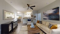 This single-floor residence is thoughtfully designed with an open-concept layout that connects the main living, dining, and kitchen areas into one cohesive space. The living room features wood-look flooring, a ceiling fan with light fixture, and ample room for comfortable seating arrangements. A dedicated bonus room, accessible from the living area, offers additional flexible living space with dual windows and a decorative fireplace, providing a quiet retreat or home office option.

The kitchen is well-equipped with white cabinetry, granite-style countertops, a subway tile backsplash, and white appliances including a refrigerator, dishwasher, range, and built-in microwave. Light tile flooring and a peninsula with bar seating enhance both functionality and flow. Adjacent to the kitchen, the dining area accommodates a full dining set and features wood-look flooring consistent with the main living spaces.

The bedroom offers carpeted flooring, a large window with blinds and curtain panels, and direct access to a full bathroom and a generously sized walk-in closet with wire shelving. Neutral gray tones throughout create a calm, cohesive ambiance across all areas of the residence.