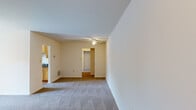 This single-floor residence offers a thoughtfully arranged layout comprising three bedrooms, two bathrooms, a living room, kitchen, entrance, two hallways, and a closet. The living room is a generously sized, open area finished with neutral wall-to-wall carpeting and a ceiling fan with light fixture. A large sliding glass door with vertical blinds fills the space with natural light and provides a view of the surrounding greenery, creating a bright and airy ambiance throughout.

The kitchen features light wood cabinetry, dark granite countertops, and wood-look flooring. Black appliances — including a refrigerator, gas range, built-in microwave, and dishwasher — complement the cabinetry. A window at the end of the kitchen brings in additional natural light.

The primary bedroom is a well-proportioned room with carpet flooring and a large window dressed with vertical blinds, offering pleasant outdoor views. The additional bedrooms are similarly carpeted and bright.

Both bathrooms are finished with tile flooring, warm wood vanity cabinets, dark granite countertops, large mirrors with overhead lighting, and wainscoting-style wall detailing. The full bathroom includes a tub-shower combination. The overall design is clean, neutral, and move-in ready.