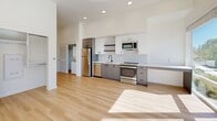 Located at 954 SW Emkay Dr in Bend, Oregon, this efficiently designed studio offers a thoughtfully arranged single-floor layout that maximizes every square foot. The open living area is anchored by a wall of large windows that flood the space with natural light and offer outdoor views, creating an airy, welcoming ambiance. Light-toned hardwood-style flooring runs throughout, complementing the clean white walls and modern aesthetic.

The kitchen is a standout feature, showcasing gray lower cabinetry paired with white upper cabinets, a classic white subway tile backsplash, and rich wood open shelving that adds warmth and character. Stainless steel appliances — including a refrigerator, electric range, dishwasher, and built-in microwave — complete the well-appointed space, along with a sleek black-fixture sink set into a light countertop.

The bathroom continues the modern, minimalist theme with light wood-look flooring, a full soaking tub with a handheld shower fixture featuring matte black hardware, and built-in open shelving for convenient storage. The unit also includes an in-unit laundry area and a dedicated closet, ensuring practical functionality within a compact footprint. Recessed lighting throughout adds a polished, contemporary finish to this efficiently crafted Bend studio.