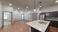 Located at 905 Palos Verdes Street in Grand Prairie, Texas, this single-story unit offers a thoughtfully designed open-concept layout that seamlessly connects the kitchen, dining, and living areas. The kitchen serves as a focal point, featuring dark espresso-toned shaker cabinets, speckled quartz countertops, a subway tile backsplash, and a full suite of stainless steel appliances including a refrigerator, electric range, and over-the-range microwave. A peninsula with an undermount sink provides additional workspace and casual seating, while pendant lights with glass fixtures add a stylish touch overhead.

The open living area is finished with warm wood-look flooring, crown molding, recessed lighting, and a ceiling fan, creating a bright and comfortable atmosphere. Large windows fitted with horizontal blinds allow natural light to filter throughout the space.

The primary bedroom is generously proportioned with plush carpeting and access to a walk-in closet featuring built-in shelving and hanging rods. The primary bathroom includes a dual-sink quartz vanity, dark cabinetry, a framed mirror, and a glass-enclosed tiled shower. A secondary bathroom mirrors the same refined aesthetic with a single-sink vanity and matching cabinetry. The overall design presents a clean, modern aesthetic with consistent finishes throughout.