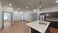 Located at 905 Palos Verdes Street in Grand Prairie, Texas, this single-story unit offers a thoughtfully designed open-concept layout that seamlessly connects the kitchen, dining, and living areas. The kitchen serves as a focal point, featuring dark espresso-toned shaker cabinets, speckled quartz countertops, a subway tile backsplash, and a full suite of stainless steel appliances including a refrigerator, electric range, and over-the-range microwave. A peninsula with an undermount sink provides additional workspace and casual seating, while pendant lights with glass fixtures add a stylish touch overhead.

The open living area is finished with warm wood-look flooring, crown molding, recessed lighting, and a ceiling fan, creating a bright and comfortable atmosphere. Large windows fitted with horizontal blinds allow natural light to filter throughout the space.

The primary bedroom is generously proportioned with plush carpeting and access to a walk-in closet featuring built-in shelving and hanging rods. The primary bathroom includes a dual-sink quartz vanity, dark cabinetry, a framed mirror, and a glass-enclosed tiled shower. A secondary bathroom mirrors the same refined aesthetic with a single-sink vanity and matching cabinetry. The overall design presents a clean, modern aesthetic with consistent finishes throughout.