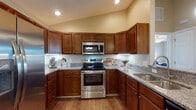Located at 4464 Professional Parkway in Groveport, Ohio, this single-floor unit offers a thoughtfully designed layout with distinct living spaces that flow naturally from one area to the next. The kitchen is a standout feature, outfitted with rich medium-toned wood cabinetry, granite countertops, stainless steel appliances including a range, over-the-range microwave, and refrigerator, all set atop warm hardwood-style flooring. Under-cabinet lighting adds both function and ambiance to the workspace.

Adjacent to the kitchen, the dining area features vaulted ceilings and hardwood-style flooring, with a chandelier overhead that adds a refined touch. The living room is carpeted and benefits from natural light through a large window, and is complemented by a ceiling fan.

The primary bedroom is generously sized with plush carpeting, a tray ceiling, ceiling fan, and a wide window. It connects to a spacious walk-in closet fitted with multi-tiered wire shelving for ample storage. The bathroom features wood-style flooring, a granite-topped vanity with rich wood cabinetry, and a tub-shower combination. A second bedroom also features carpet, a ceiling fan, natural light, and a closet with built-in shelving.
