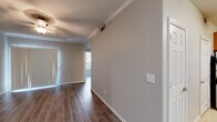 This single-floor residence offers a clean, functional layout designed for comfortable everyday living. The main living area features light wood-look laminate flooring, neutral-toned walls, crown molding, and a ceiling fan, creating a bright and open atmosphere. Vertical blinds along a sliding glass door allow natural light to flow in while providing access to the outdoors.

The kitchen is well-equipped and thoughtfully designed, featuring warm wood cabinetry with ample storage, granite-style countertops, a breakfast bar peninsula, and stainless steel appliances including a refrigerator, microwave, and electric range. A dishwasher and tile flooring complete the practical kitchen space. A decorative wine rack built into the upper cabinetry adds a charming touch.

The bedroom offers a comfortable retreat with light wood-look flooring, neutral walls, and a mirrored sliding closet door that enhances the sense of space. An additional versatile room with built-in cabinetry provides flexible use as a home office or den.

The bathroom is finished with tile flooring, a tub-shower combination accented by white and brown tile surrounds, a granite-topped vanity with warm wood cabinetry, and a large mirror. Throughout, the space maintains a consistent, neutral palette that is both welcoming and easy to personalize.
