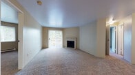 This single-floor residence offers a practical and comfortable layout with a neutral color palette throughout. The spacious living room serves as the heart of the home, featuring plush wall-to-wall carpeting, a tile-surround fireplace, and a sliding glass door fitted with vertical blinds that fills the space with natural light and provides outdoor access. A hallway connects the living area to the rest of the home.

The galley-style kitchen is efficiently designed with white cabinetry, a stainless steel sink, laminate countertops, and wood-look flooring. White appliances include a range, refrigerator, and dishwasher, while a pass-through or peninsula connects the kitchen to the adjacent living and dining area, which also features a ceiling fan.

The bedrooms are carpeted and well-proportioned, each offering natural light. One bedroom includes a baseboard heater beneath a window, while another features a reach-in closet with built-in shelving. Two bathrooms serve the unit, both finished with wood-look flooring, white cabinetry, and light countertops. One includes a tub-shower combination, while the other functions as a half or three-quarter bath. The overall ambiance is clean, neutral, and move-in ready.
