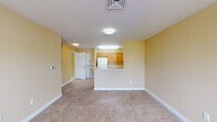 Located at 697 Ferry Ave in Camden, NJ, this single-floor unit offers a well-organized layout designed for comfortable everyday living. The interior is unified by warm yellow-toned walls and white trim, creating a bright and cohesive aesthetic throughout.

The open living area is generously proportioned, featuring soft wall-to-wall carpeting and multiple windows that allow natural light to fill the space. A peninsula counter separates the living area from the kitchen, providing a functional transition between the two spaces.

The kitchen is designed with ample storage in mind, featuring a full complement of warm wood cabinetry — both upper and lower — that wraps around in a U-shaped configuration. Light countertops, a white refrigerator, an electric range with overhead exhaust, and easy-to-maintain tile flooring complete the kitchen's practical setup.

The bedrooms continue the carpeted flooring and warm wall palette, each benefiting from natural light through double-pane windows. The bathroom is finished with white tile flooring, a full soaking tub with tiled surround, a wood-cabinet vanity with a white countertop, and accessibility-focused grab bars thoughtfully installed near the tub and toilet. The overall ambiance of the unit is clean, functional, and move-in ready.