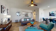 This single-story residence is designed with an open-concept layout that connects the living, dining, and kitchen areas into one cohesive, flowing space. The living room serves as the heart of the home, featuring a ceiling fan, a fireplace with a clean-lined mantel, and large windows dressed with patterned drapes that invite natural light. Wood-look plank flooring extends throughout the entire unit, providing a warm, consistent foundation across every room.

The kitchen is outfitted with gray shaker-style cabinetry, white countertops, a white subway tile backsplash, and stainless steel appliances, including a range, over-the-range microwave, and refrigerator. A pass-through opening visually connects the kitchen to the living area, enhancing the open feel.

The dining area sits adjacent to the living room, offering a defined space for everyday meals or entertaining. Multiple bedrooms provide comfortable, private retreats, each featuring ceiling fans or overhead lighting, natural light from windows with blinds, and ample floor space. The bathroom includes a wide dual-sink vanity with gray cabinetry, a large mirror, white countertops, and wood-look flooring, delivering a clean, functional design.