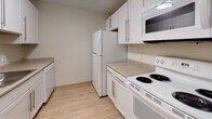 Located at 30 Rockingham Ave in the West Roxbury neighborhood of Boston, MA, this single-floor unit offers a clean, modern aesthetic throughout. Light wood-style flooring flows seamlessly across all areas, creating a cohesive and airy feel.

The kitchen is equipped with white cabinetry featuring contemporary hardware, laminate countertops, and a full suite of white appliances including a refrigerator, electric range, built-in microwave, and dishwasher. The layout is efficiently designed to maximize workspace and storage.

The open living area is generously proportioned, bathed in natural light through large windows that frame views of surrounding trees, lending a sense of calm and privacy. Baseboard heating runs along the perimeter, ensuring comfort throughout the seasons.

A dedicated bedroom provides a quiet retreat with its own window overlooking the wooded scenery, continuing the light flooring found throughout the unit. Additional storage is accessible via a closet off the main living area.

The full bathroom is finished with white square tile in the tub/shower surround, neutral floor tile, a white vanity with integrated sink, and brushed nickel grab bars and fixtures. The overall design of the space prioritizes functionality and clean, understated style, making it a comfortable and practical Boston residence.