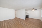 Located at 425 E Bradley Ave in El Cajon, CA, this 2-bedroom, 1-bathroom unit offers a clean, modern interior with thoughtful updates throughout. Light wood flooring runs consistently across the entire space, complementing the bright white walls and textured ceilings to create a fresh, airy atmosphere. The open living and dining area is well-lit by large windows fitted with horizontal blinds, and a ceiling fan provides added comfort. A wall-mounted AC unit ensures year-round climate control. Sliding glass doors lead directly to a private patio, filling the living space with natural light. The galley-style kitchen is efficiently designed with white shaker cabinetry, granite countertops, a classic subway tile backsplash, and stainless steel appliances including a range, microwave, and refrigerator. Both bedrooms are generously proportioned, with the primary bedroom offering a spacious layout and a sliding-door closet. Additional closet space is available throughout the unit, totaling three closets. The bathroom features a subway-tiled tub/shower surround, granite vanity top, and gray cabinetry, maintaining the consistent modern aesthetic found throughout the home. A connecting hallway ties all rooms together in a practical, well-organized floor plan.