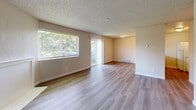 Located at 1117A 99th St Ct in Tacoma, WA, this single-floor, 2-bedroom, 1-bathroom residence offers a practical and comfortable layout across a well-utilized floor plan. The interior features light-toned luxury vinyl plank flooring throughout, paired with neutral warm-beige walls and textured ceilings that lend a clean, cohesive aesthetic to every room.

The combined living and dining area is generously proportioned, bathed in natural light from large windows and a sliding glass door that opens to an outdoor patio. Baseboard heaters are present throughout the unit, providing consistent climate control. A pass-through kitchen connects openly to the living area, featuring white cabinetry, a countertop with a built-in sink, a gas range, and a refrigerator — making the space both functional and social in design.

The two bedrooms are well-sized, each equipped with windows that invite natural light and baseboard heating. The primary bedroom includes access to a dedicated closet as well as a direct entry to the full bathroom. The bathroom is equipped with a single-sink vanity with a light countertop, a toilet, and a tub-shower combination. A separate closet provides additional storage within the unit, rounding out the practical offerings of this straightforward Tacoma residence.