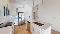 Located at 650 E Brooklyn Village Ave in Charlotte's vibrant Brooklyn Village neighborhood, this single-floor residence offers a clean, contemporary design throughout. Warm wood-style flooring flows seamlessly across the living areas, complemented by crisp white walls and abundant natural light streaming through large windows fitted with blinds, framing elevated views of the surrounding cityscape.

The kitchen is a standout feature, showcasing white shaker-style cabinetry, quartz countertops, a full suite of stainless steel appliances including a side-by-side refrigerator, range, microwave, and dishwasher, as well as a center island with an undermount sink and stylish pendant lighting overhead. A subway tile backsplash and built-in wine rack add refined finishing touches.

The bedrooms are bright and well-proportioned, each benefiting from natural light and views of the Charlotte skyline. The primary suite includes a spacious walk-in closet with wire shelving and a well-appointed en-suite bathroom featuring a glass-enclosed tile shower, extended vanity with quartz counters, and ample cabinet storage. A second full bathroom offers a soaking tub with tile surround. Clean lines, neutral tones, and quality finishes define the overall ambiance of this polished urban residence.