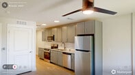 Located at 5440 Atlantic Springs Rd in Raleigh, NC, this single-floor unit offers a thoughtfully designed layout that makes efficient use of its compact footprint. The space includes two kitchen areas, a full bathroom, and a closet, all finished with a cohesive, contemporary aesthetic.

The kitchen areas are well-appointed with gray shaker-style cabinetry, granite-look countertops, and a white subway tile backsplash. Stainless steel appliances — including a refrigerator, electric range, over-the-range microwave, and dishwasher — provide a fully functional cooking environment. Recessed lighting and light wood-look flooring carry throughout, lending the space a clean, modern feel. A window and sliding door access point introduce natural light and outdoor views, enhancing the sense of openness.

The bathroom features wood-look tile flooring, a vanity with granite-style countertops and dark cabinetry accented by brushed gold hardware, a bathtub with a shower curtain rod, and a toilet. The neutral white walls and recessed lighting create a bright, clean atmosphere. The closet provides additional storage, completing this efficiently organized unit.