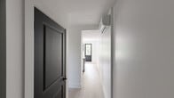 Located at 4900 Ch De La Côte-Des-Neiges in Montréal's Côte-des-Neiges neighbourhood, this thoughtfully designed 2-bedroom, 1-bathroom unit delivers a clean, modern aesthetic across a compact yet efficient single-floor layout. Light-toned hardwood flooring runs throughout, complementing the crisp white walls and creating a bright, cohesive feel.

The kitchen is a standout feature, anchored by a dramatic black marble-veined countertop island that doubles as a dining surface. White flat-panel cabinetry reaches the ceiling for ample storage, while stainless steel appliances, a built-in microwave, and a sleek industrial-style faucet complete the contemporary look. A window above the counter draws in natural light.

Both bedrooms are finished in the same light hardwood and white palette. The primary bedroom offers a mirrored sliding closet with black-framed hardware, adding depth to the space. Bold navy-black panel doors serve as a sharp design accent throughout the unit. The second bedroom also benefits from natural light through a black-framed window.

The bathroom is elegantly appointed with large-format marble-look porcelain tiles on both the floors and walls, a glass-enclosed tub-shower with matte black fixtures, a wood-toned vanity with a dark countertop, and a natural light source via a window. Three hallways connect the rooms efficiently, rounding out this well-appointed modern residence.