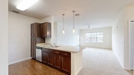 Located in Orange Park, FL, this two-story, two-bedroom, two-bathroom home offers a well-organized layout spread across two levels. The main living area on the upper floor is bright and open, with large windows allowing generous natural light and ceiling fans providing comfort throughout. The kitchen is a standout feature, showcasing rich dark wood cabinetry, granite-style countertops, hardwood-style flooring, stainless steel appliances, and a peninsula with pendant lighting that connects seamlessly to the open living area. The bathrooms are finished with tile flooring, granite-topped vanities, and full tub-shower combinations. Both bedrooms are carpeted and well-sized, with the primary bedroom offering a spacious walk-in closet equipped with built-in wire shelving on multiple walls, providing ample storage. The second bedroom is equally comfortable with its own closet access. A dedicated laundry room adds everyday convenience. Carpeted staircases with white handrails connect the entry-level foyer to the main living floor above. Multiple hallways provide smooth circulation throughout the home. The clean, neutral color palette and consistent finishes give the space a cohesive and move-in ready feel.