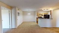 Located in Jacksonville, FL (32218), this single-floor home offers a functional and comfortable layout. The open-concept living and dining area is generously sized, featuring plush carpeting, a textured ceiling, and a chandelier overhead. A tiled fireplace serves as a focal point in the living room, which also includes a sliding glass door providing direct access to an outdoor area and allowing natural light to fill the space. An additional bedroom features its own sliding glass door with vertical blinds, offering outdoor views and added brightness. The galley-style kitchen is well-appointed with light wood cabinetry, dark countertops, wood-look flooring, and black appliances including a range, refrigerator, and dishwasher. A pass-through peninsula connects the kitchen to the dining and living areas. The home includes two full bathrooms — one with a tub/shower combination and wood-look flooring, and another featuring tile-surround walls, a soaking tub, and a single vanity. A spacious walk-in closet with dual wire shelving systems provides ample storage. The interior hallway connects all areas efficiently, completing this well-organized single-level home.